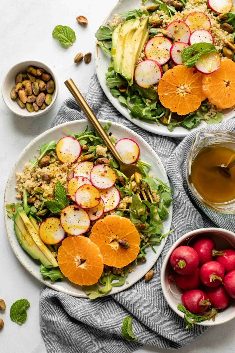 Two plates of summer quinoa salads with tangerines and radishes.