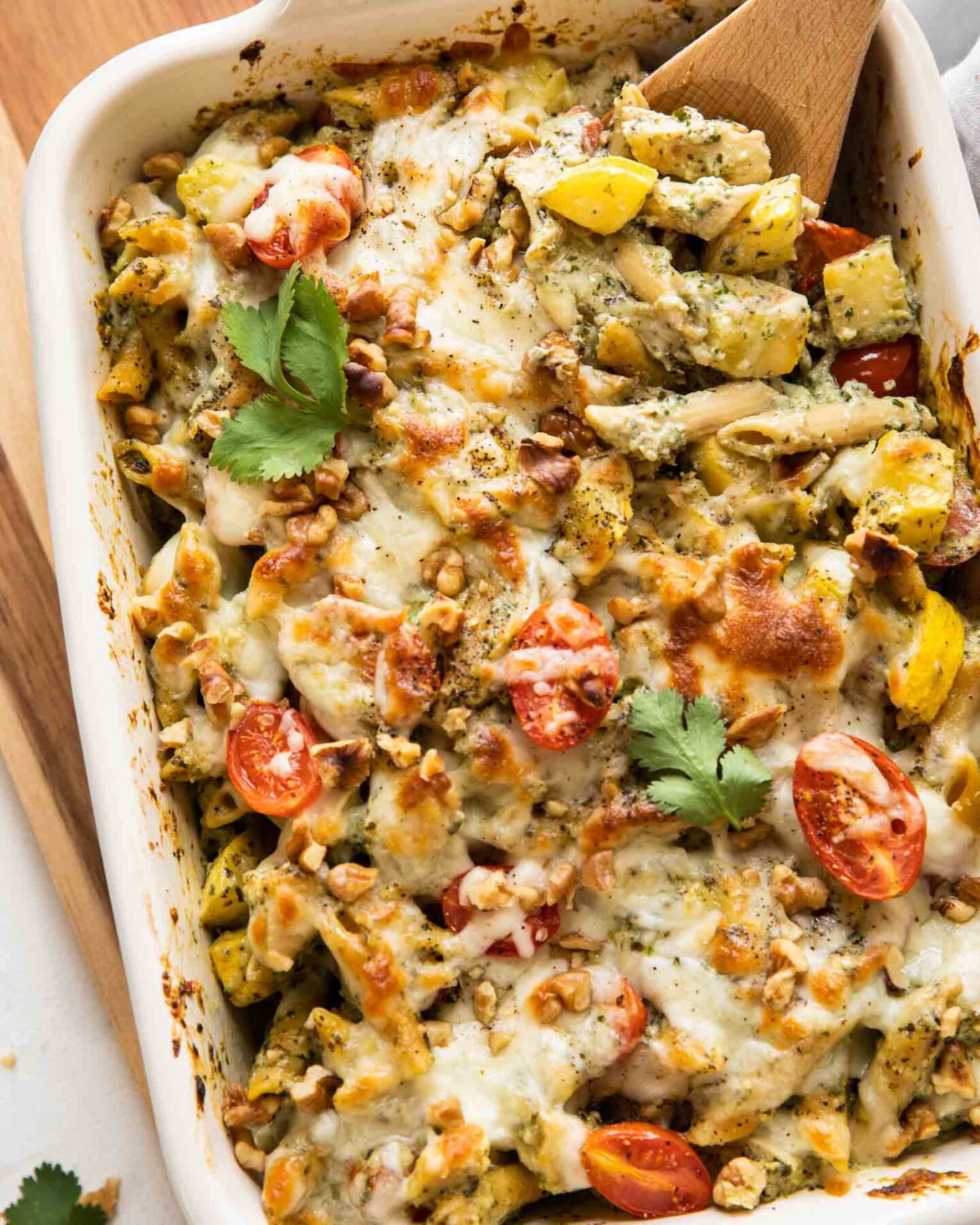 Top shot of Chicken Pesto Pasta Bake with a wooden spoon.