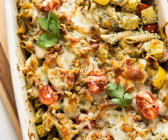 Top shot of Chicken Pesto Pasta Bake with a wooden spoon.
