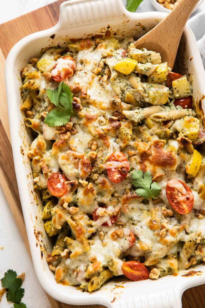 Top shot of Chicken Pesto Pasta Bake with a wooden spoon.