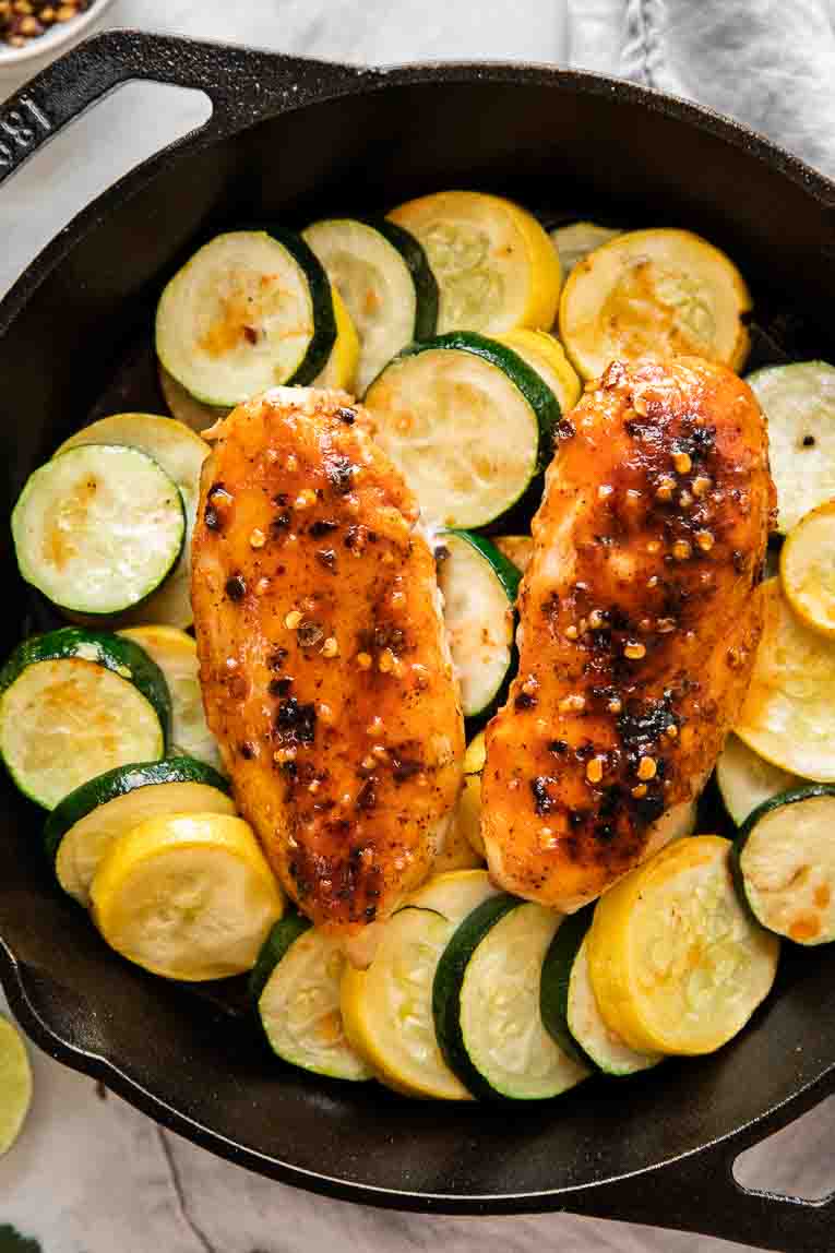 Zucchini, squash, and chicken in a skillet with hot honey sauce.