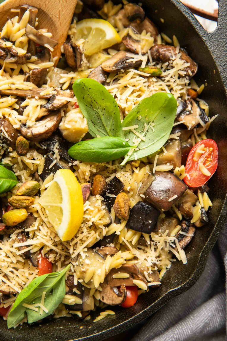 Close up of Lemon Garlic Eggplant Mushroom Orzo pasta in a skillet with basil.