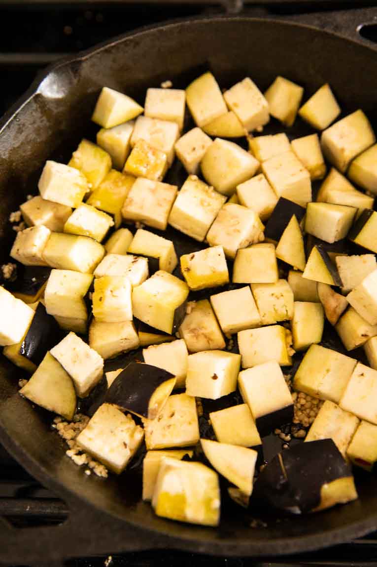 Cubed eggplant being cooked in a skillet.