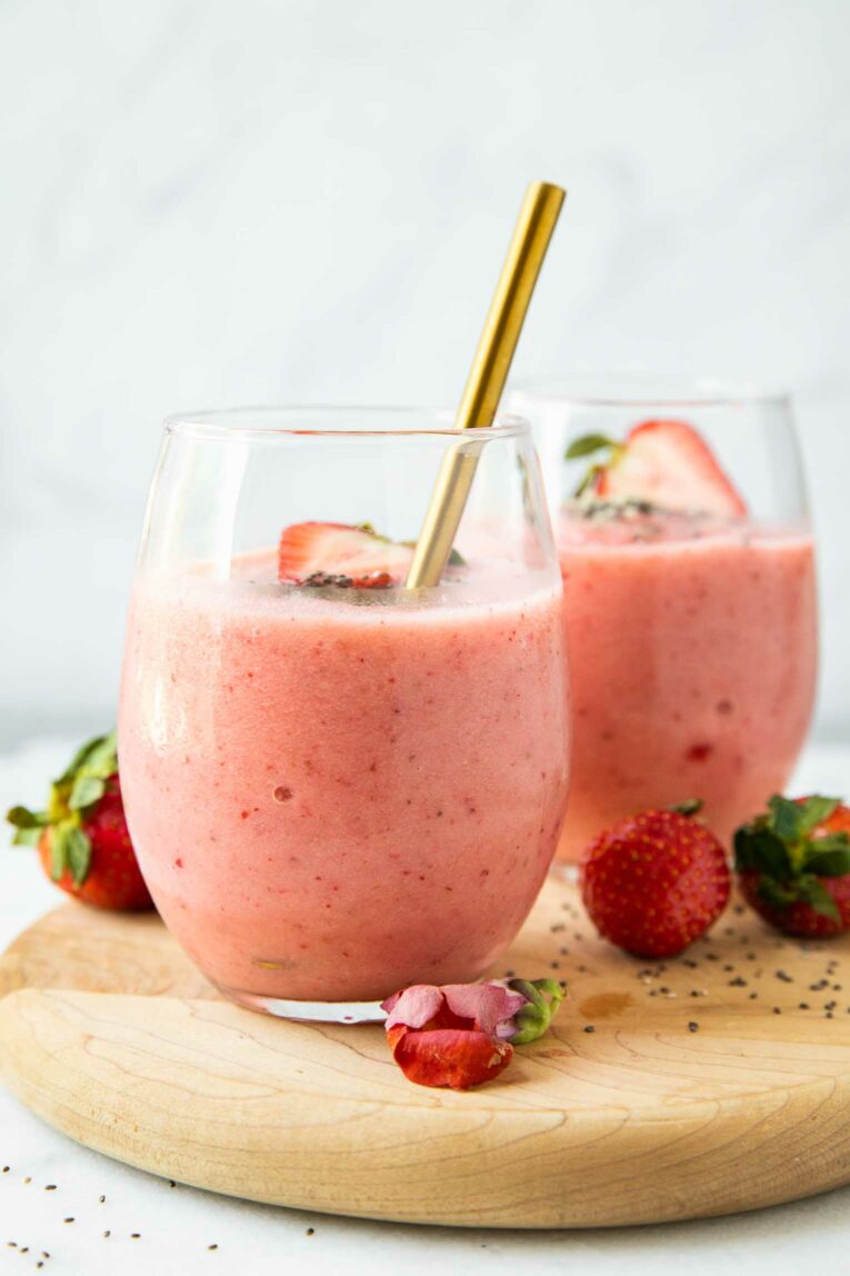 Across shot of Strawberry Pineapple Smoothie in two glass cups with a spoon.