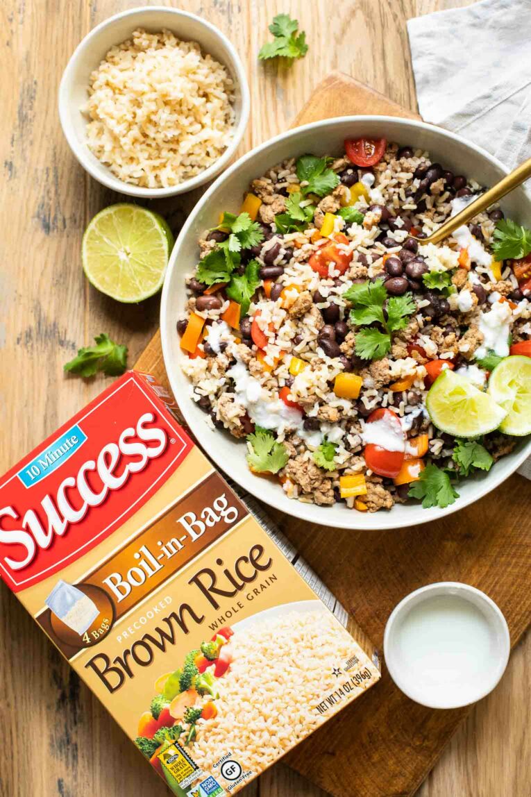 Top shot of taco bowls with brown rice on a wood table.