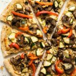 Vegan Hummus pizza with mushrooms, zucchini, and red peppers.