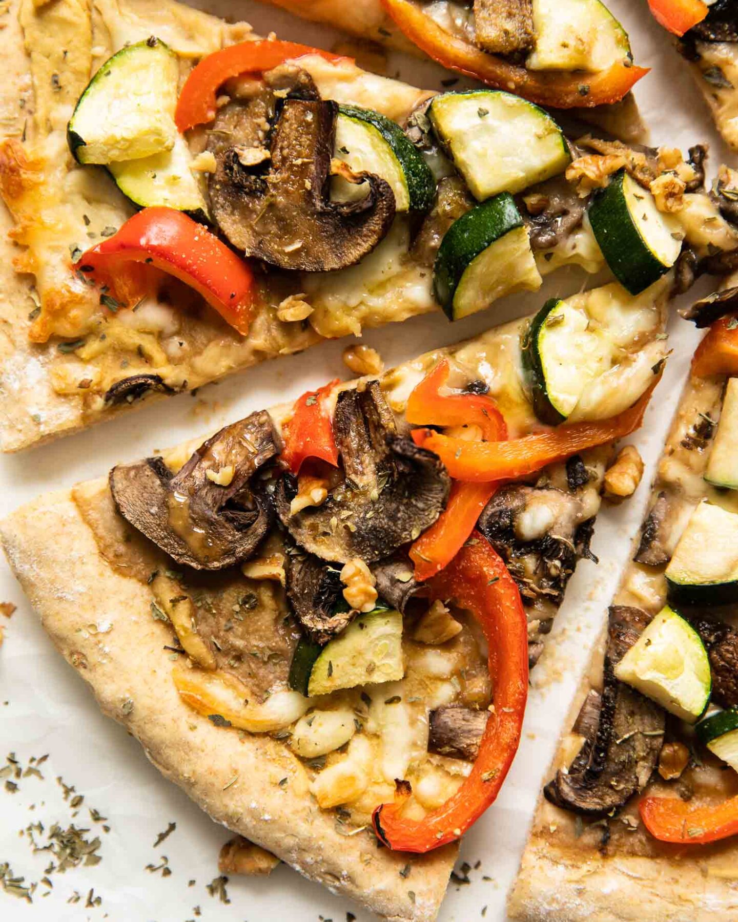 Slices of Vegan Red Pepper Hummus Pizza on parchment paper.