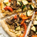 Slices of Vegan Red Pepper Hummus Pizza on parchment paper.