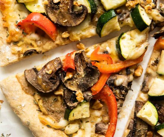Slices of Vegan Red Pepper Hummus Pizza on parchment paper.