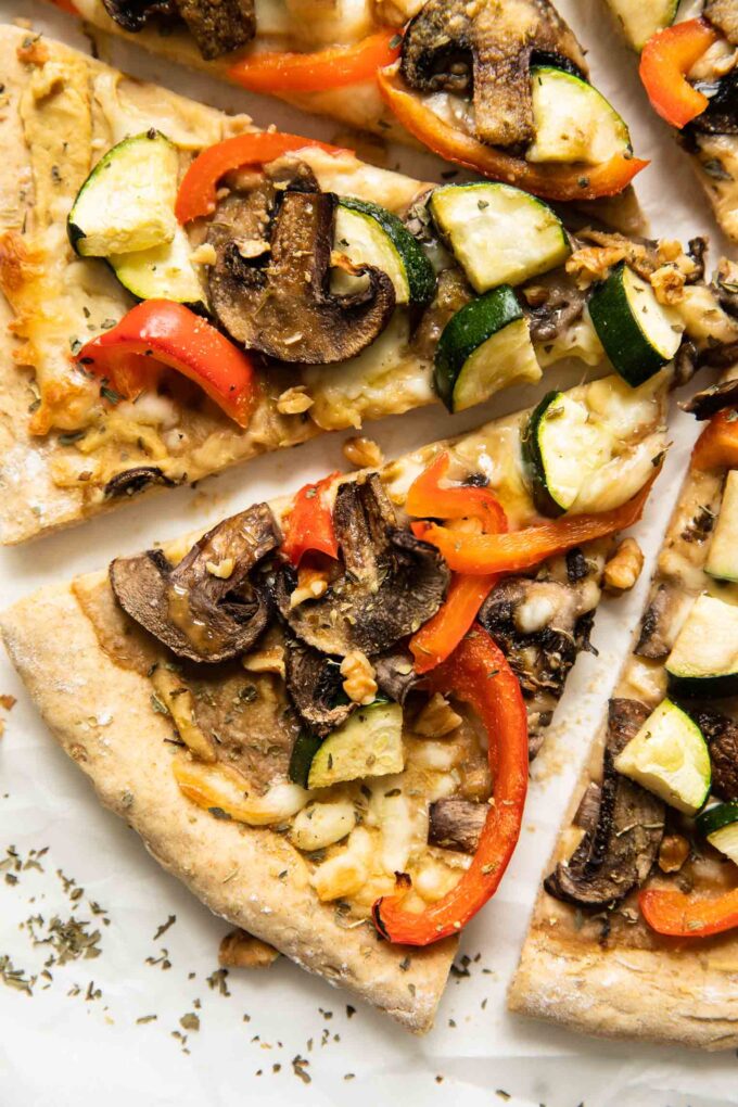 Slices of Vegan Red Pepper Hummus Pizza on parchment paper.