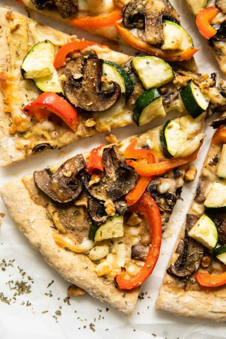 Slices of Vegan Red Pepper Hummus Pizza on parchment paper.
