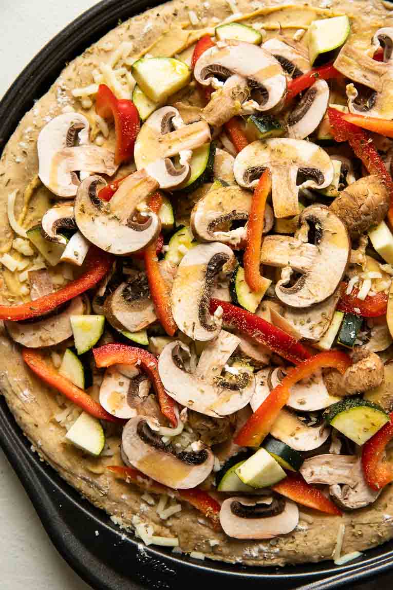 Vegan Pizza toppings on a raw pizza crust.