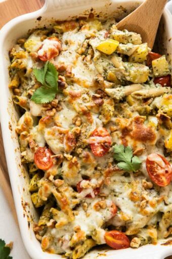 Top shot of Chicken Pesto Pasta Bake with a wooden spoon.