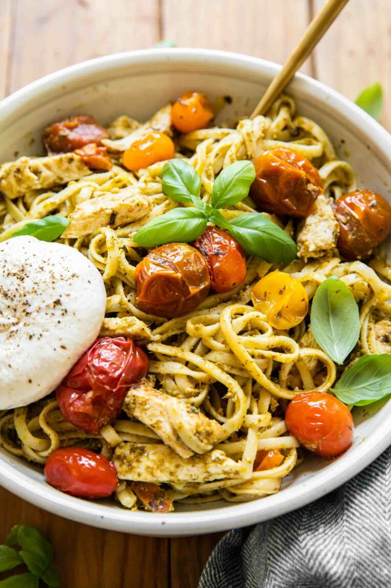 Angled shot of pesto burrata pasta with chicken and tomatoes.