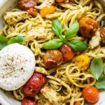 Top shot of Chicken Tomato Pesto Burrata Pasta in a white bowl with a fork.