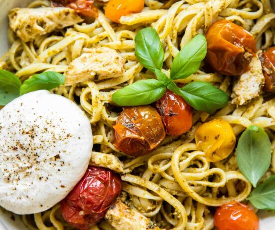 Top shot of Chicken Tomato Pesto Burrata Pasta in a white bowl with a fork.