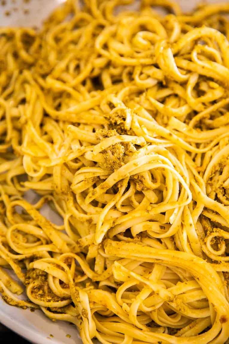 Linguine pasta tossed with pesto in a pan.