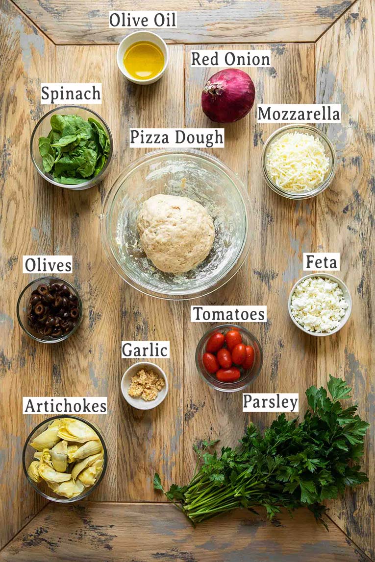 Ingredients for easy mediterranean pizza recipe on a wood table.
