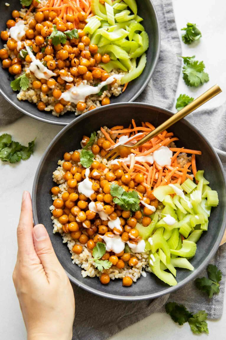 Two Hot Honey Chickpea Bowls with hand holding one of them.