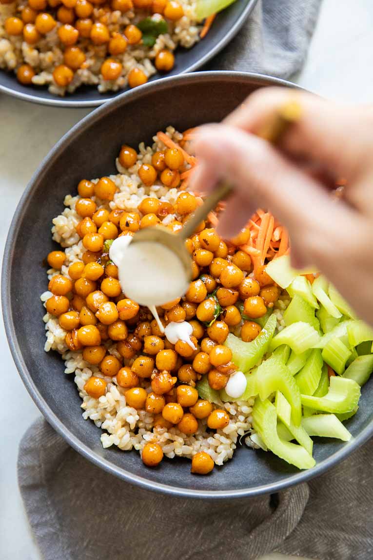 Healthy ranch dressing being drizzled over hot honey chickpeas.