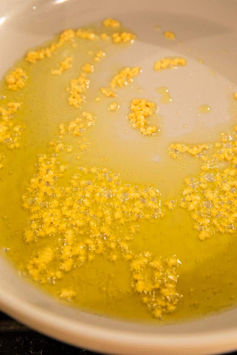 Oil, garlic, and salt being sautéed in a pan.