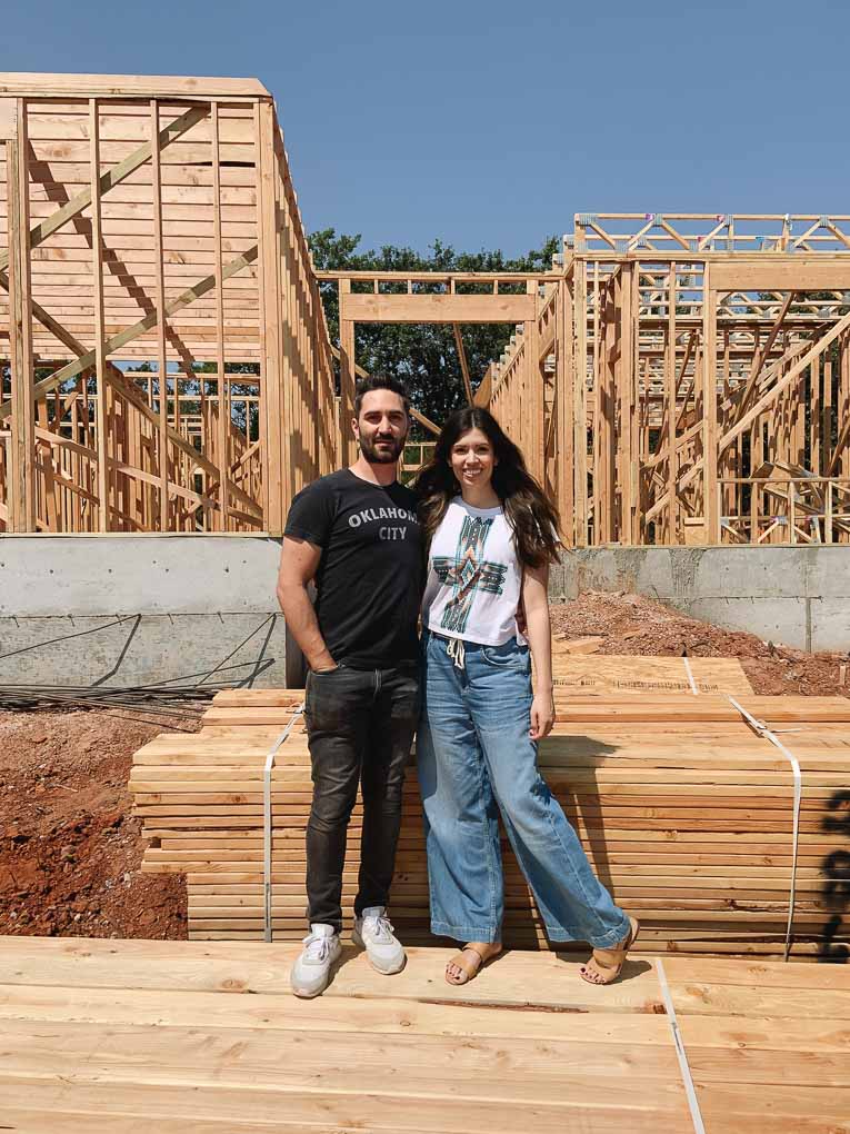 Couple in front of framed house.