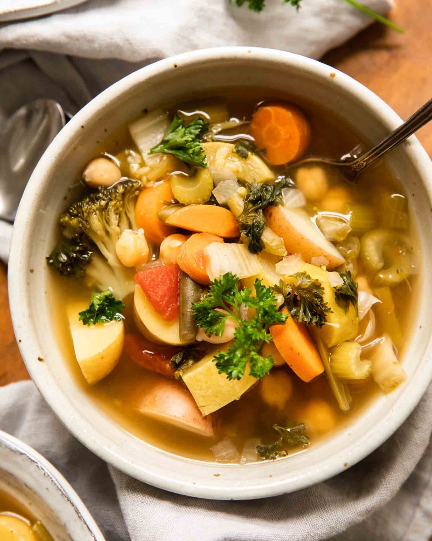 Top shot of Crockpot Vegetable Soup in a white bowl with a napkin and spoon.