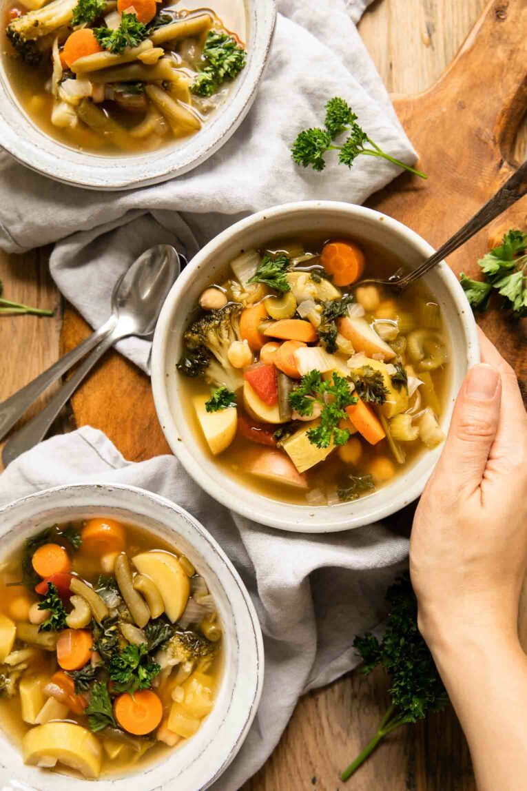 Hand holding bowl of vegetable soup made in the slow cooker.