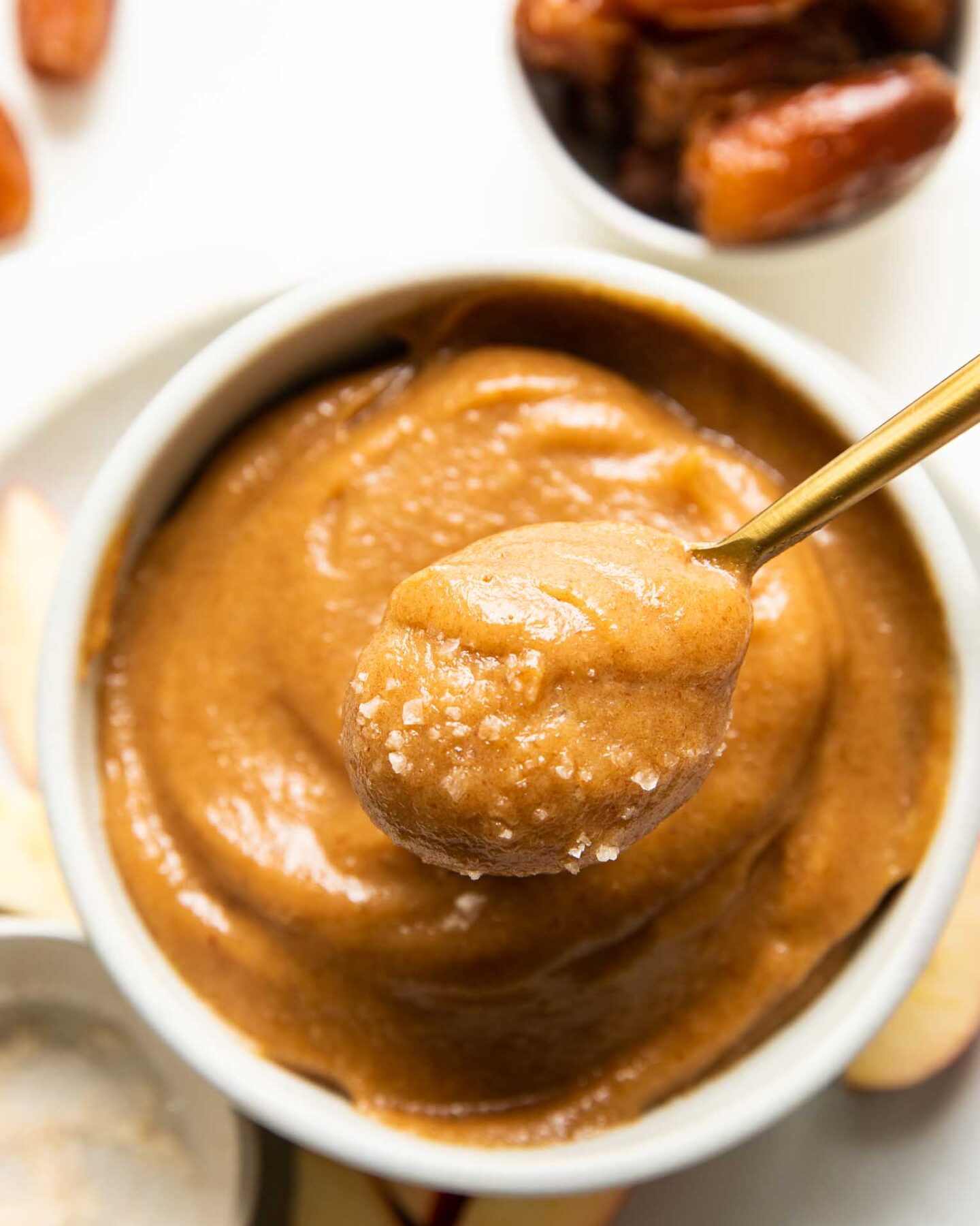 Top shot of spoon removing vegan caramel out of a white bowl.