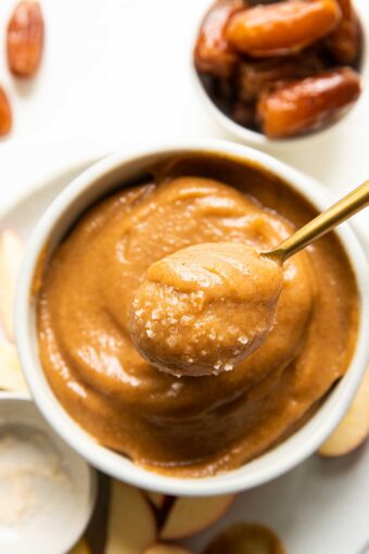 Top shot of spoon removing vegan caramel out of a white bowl.