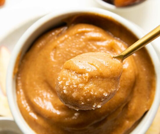 Top shot of spoon removing vegan caramel out of a white bowl.
