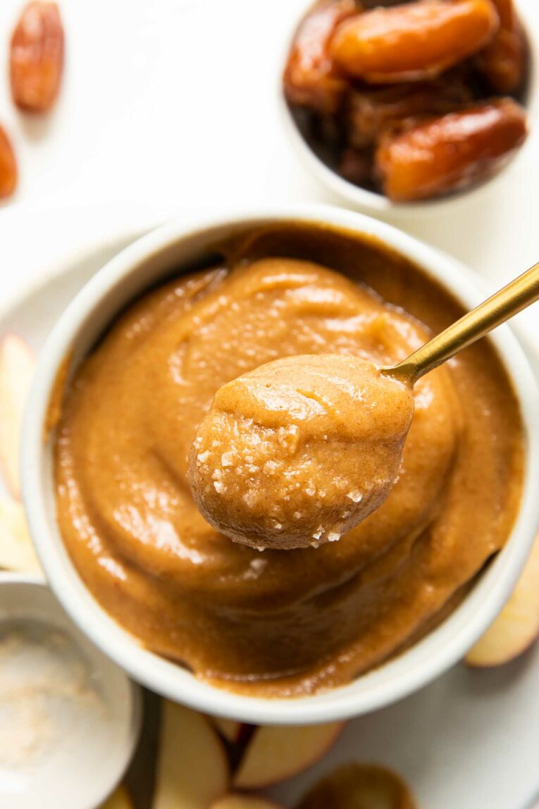 Top shot of spoon removing vegan caramel out of a white bowl.