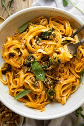 Creamy Pumpkin Pasta in a white bowl with forks.