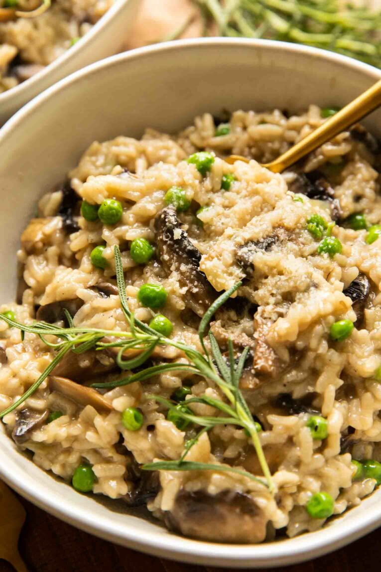 Angled close up of Instant Pot risotto with mushrooms, peas, and rosemary.