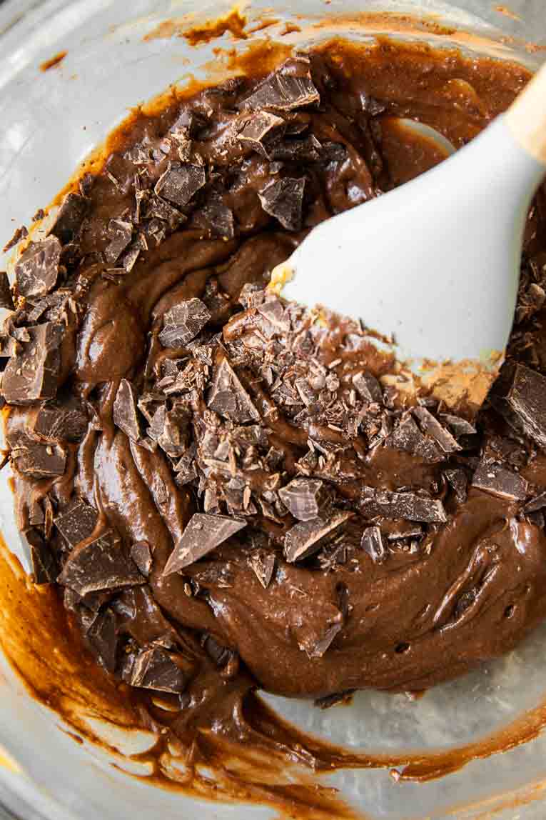 Chocolate fudge brownie batter being mixed in a glass bowl.