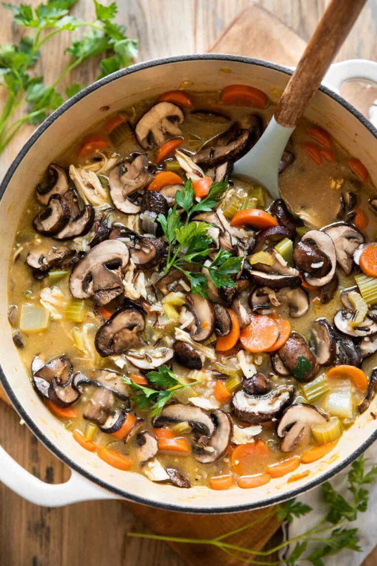 Top view of leftover turkey wild rice soup with a creamy sauce, mushrooms, and parsley.