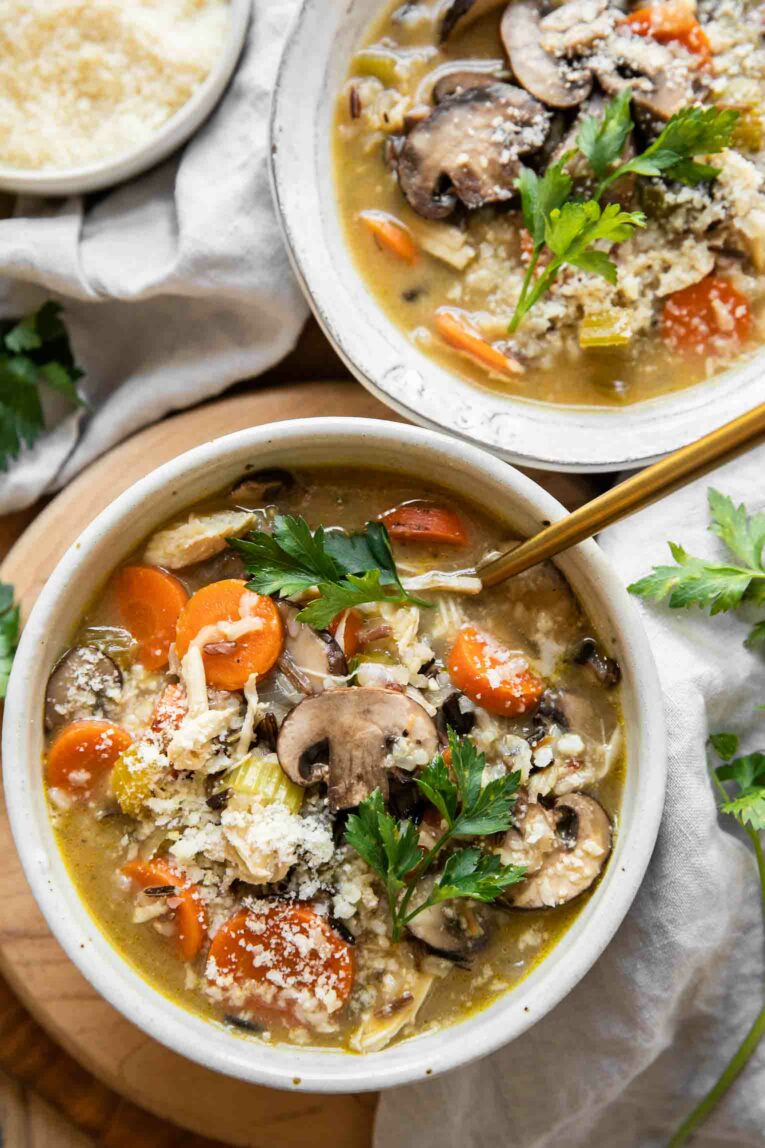 Bowls of turkey wild rice soup with mushrooms, vegetables, parsley, and a creamy broth.