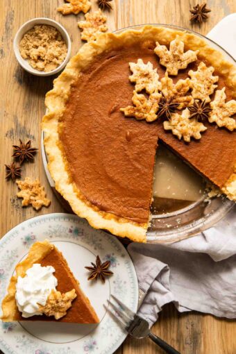 Slice of dairy free pumpkin pie on a plate next to entire pie.