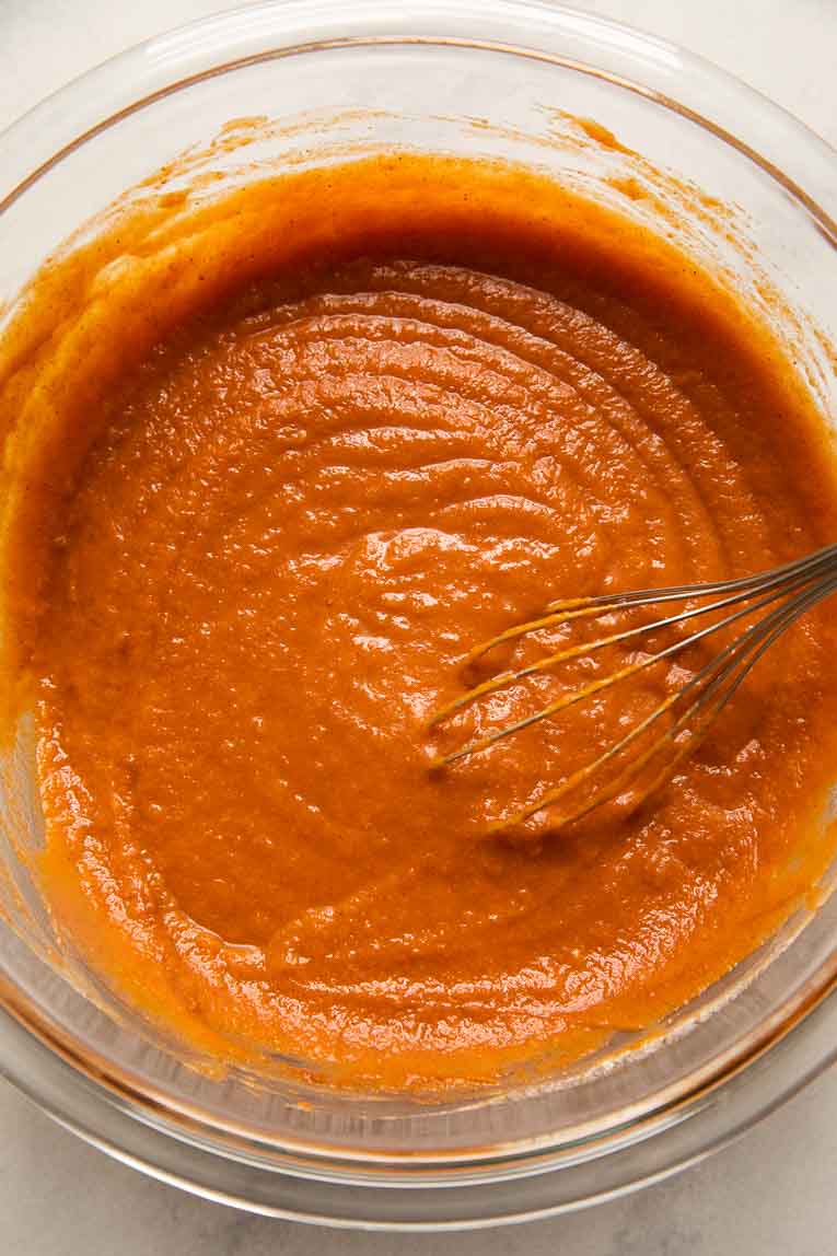 Pumpkin Pie filling being mixed in a glass bowl.