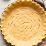 Top shot of vegan pie crust in a pan with a rolling pin.