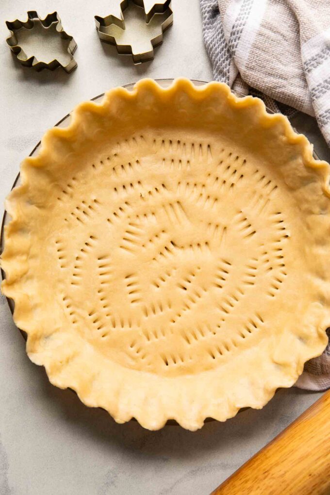 Top shot of vegan pie crust in a pan with a rolling pin.