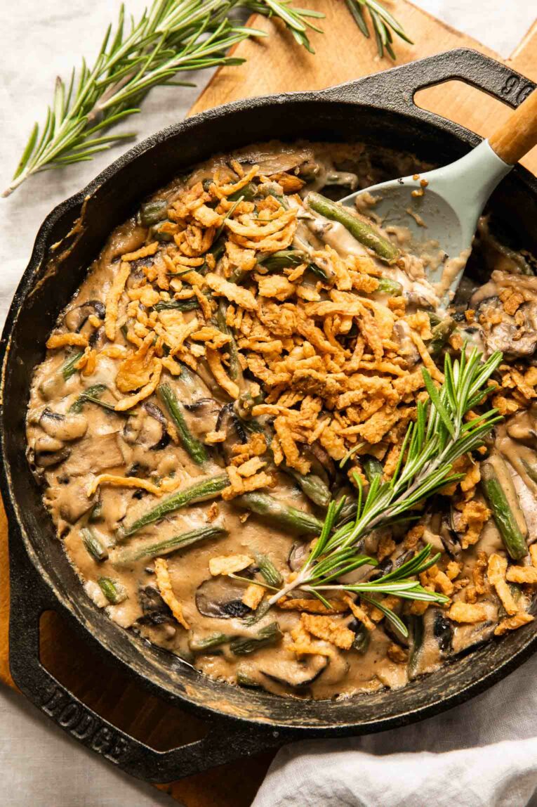Top shot of vegan green bean casserole in a skillet with a wooden spoon.