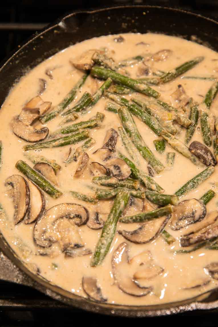 Green beans, mushrooms, and cream sauce in a cast iron skillet.