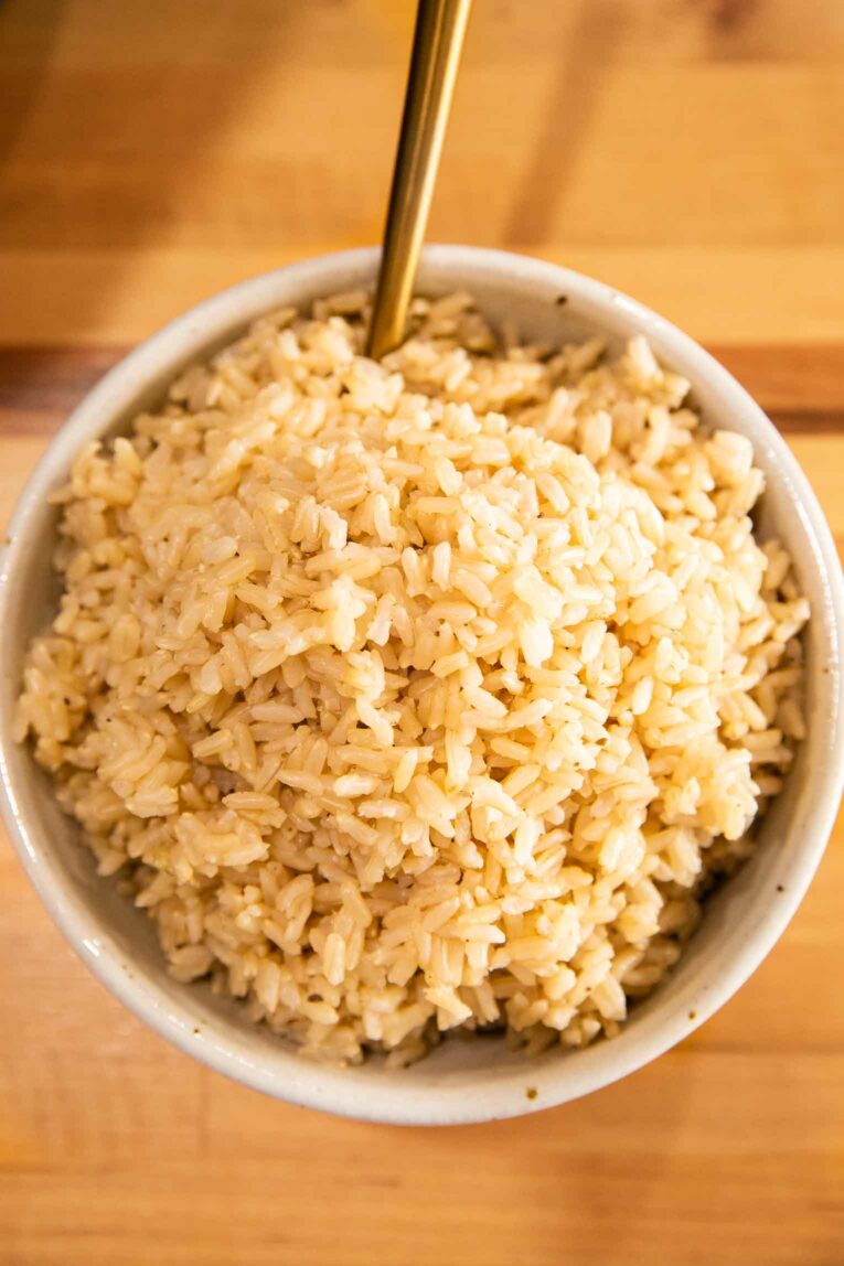 Top shot of cooked brown rice in a white bowl.