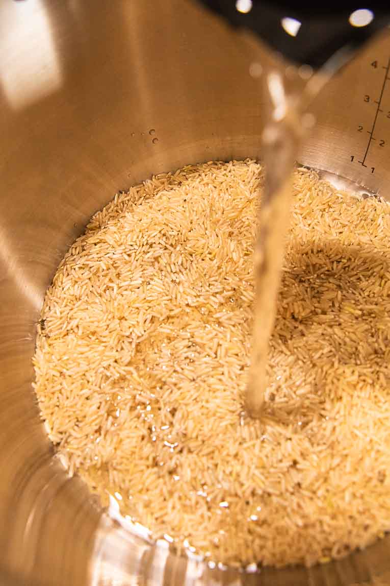 Water being poured into an Instant Pot with brown rice.