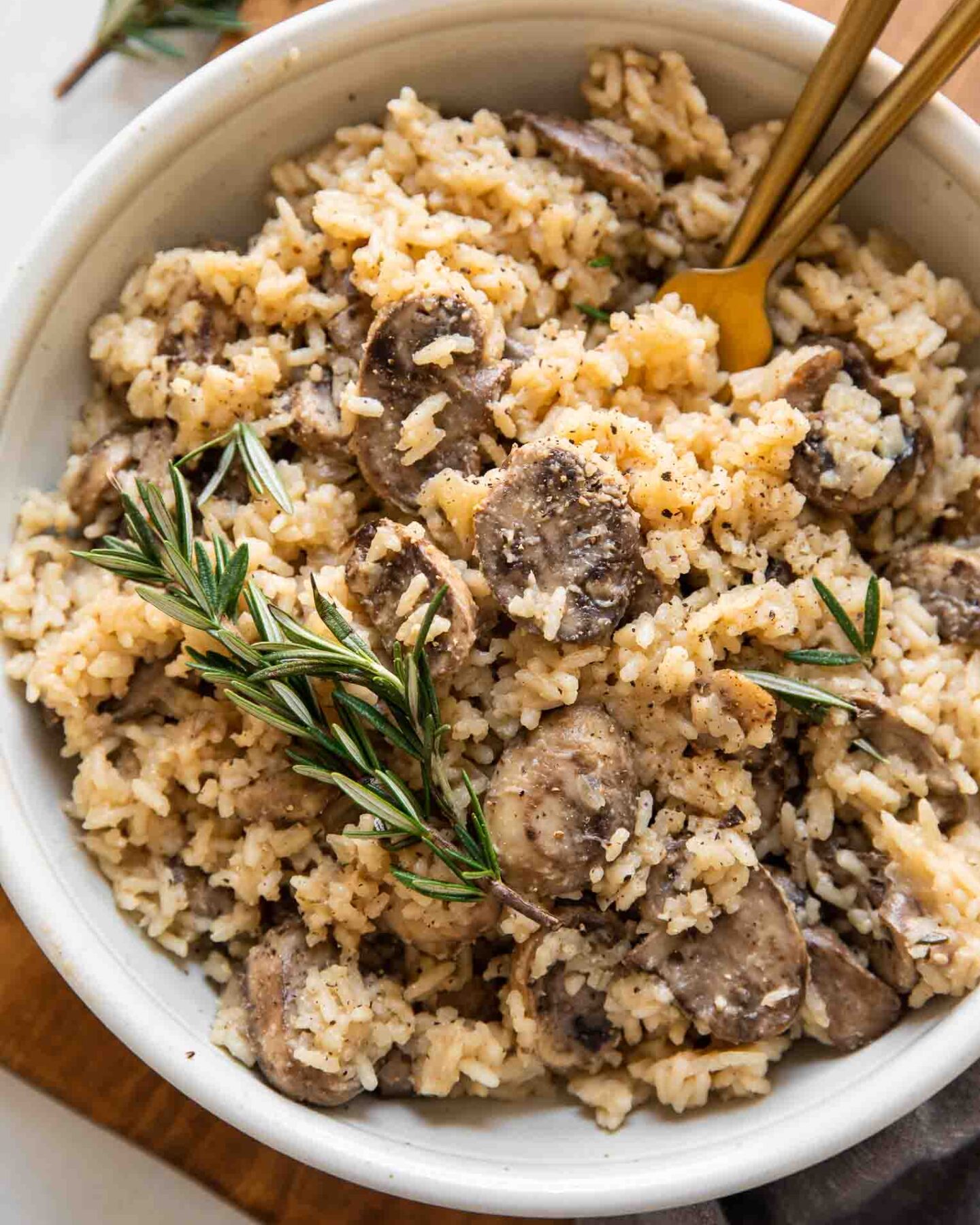 Rosemary Mushroom Rice Pilaf in a white bowl with two forks.
