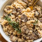 Rosemary Mushroom Rice Pilaf in a white bowl with two forks.
