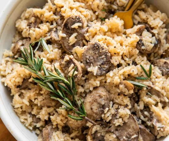 Rosemary Mushroom Rice Pilaf in a white bowl with two forks.