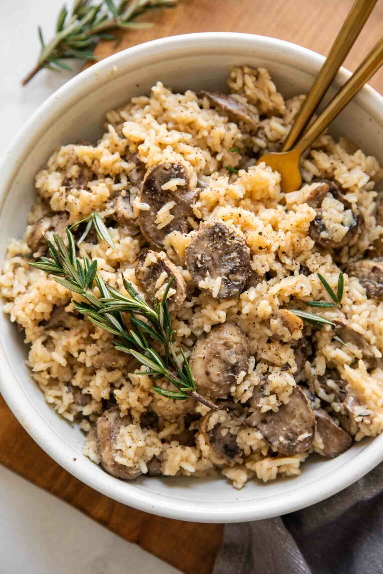 Rosemary Mushroom Rice Pilaf in a white bowl with two forks.