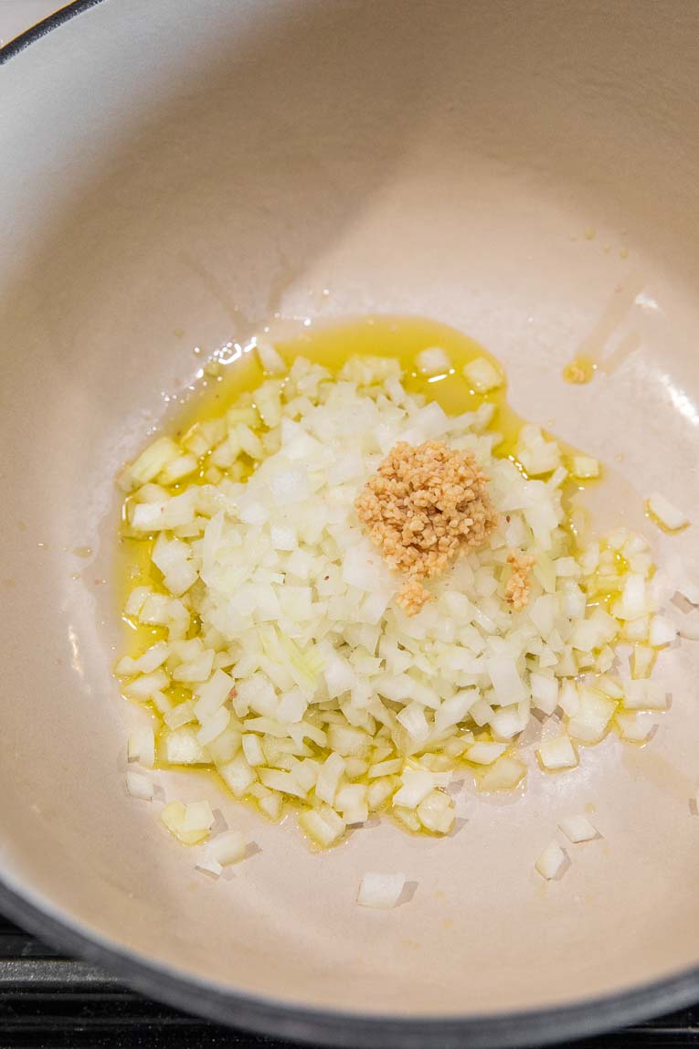 Onions and garlic being cooked in a dutch oven.